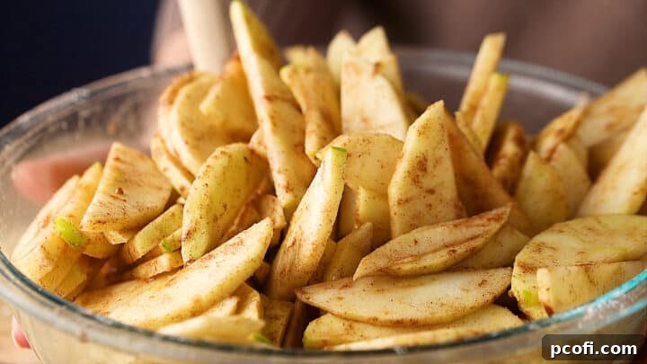 Sliced apples, tossed together with sugar, flour, and spices to make apple pie filling, ready to be baked.