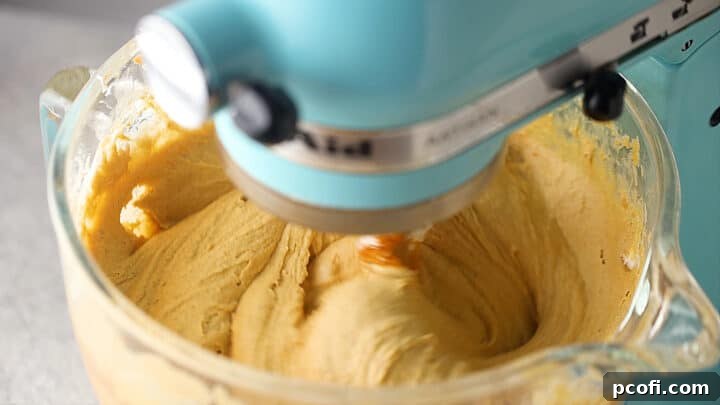 Beating pumpkin cake batter with an electric mixer.