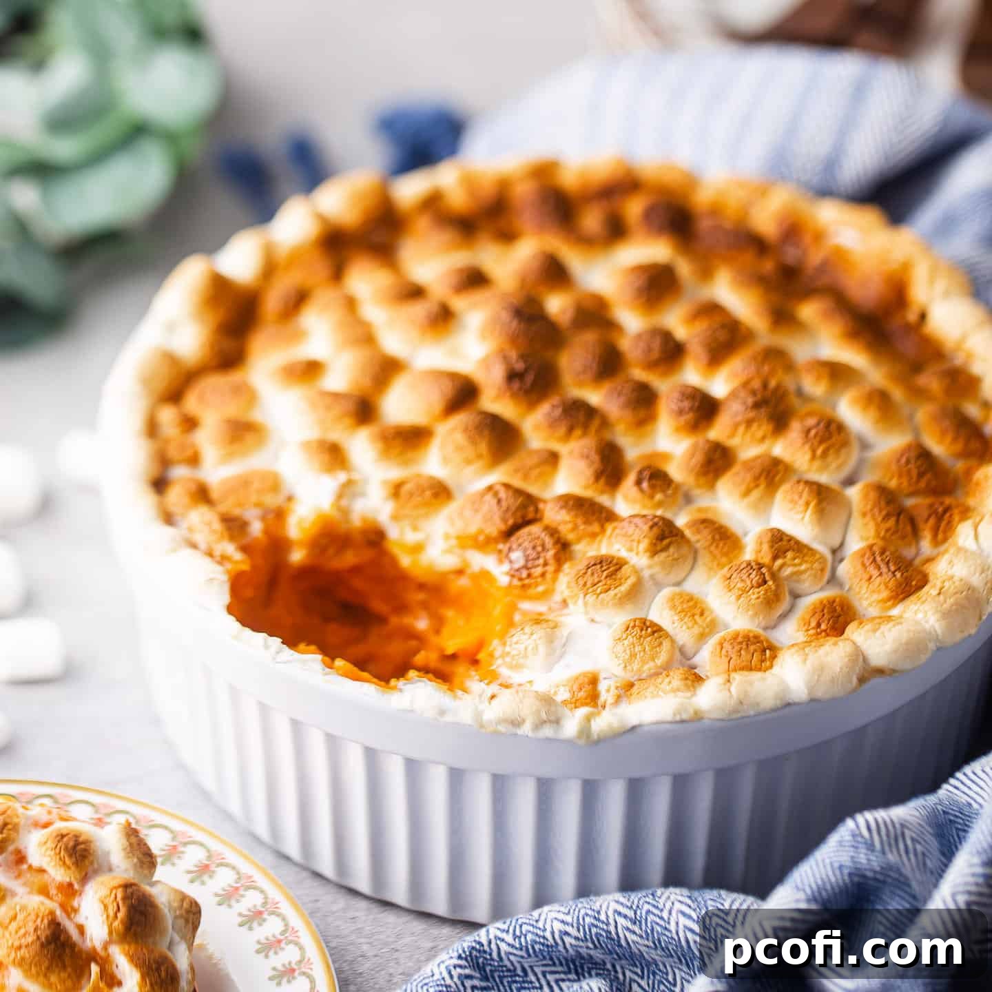 Sweet potato casserole in a souffle dish with a blue cloth, ready to be served for a holiday meal.