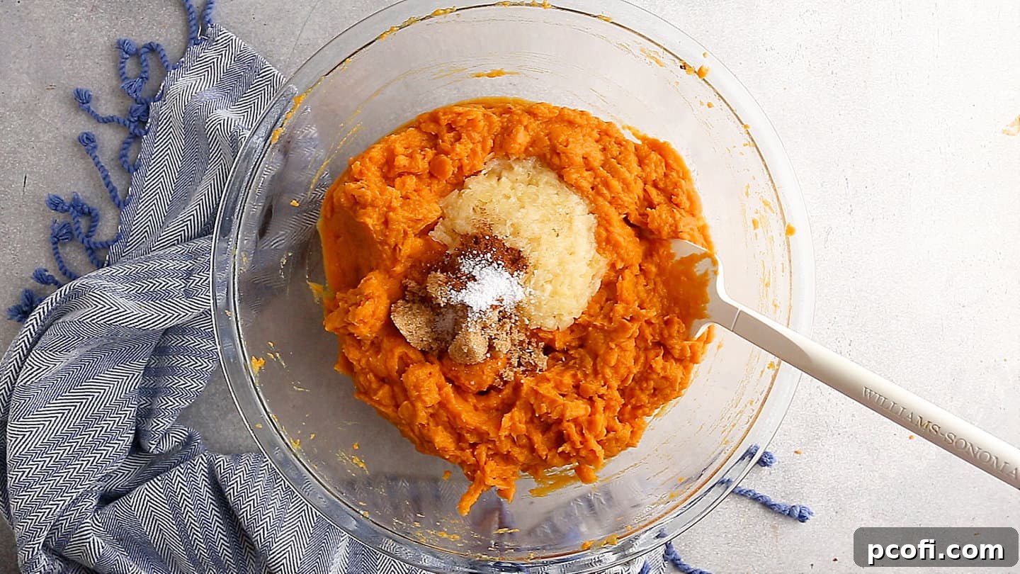 Mashed sweet potatoes with crushed pineapple, brown sugar, cinnamon, and salt in a mixing bowl.