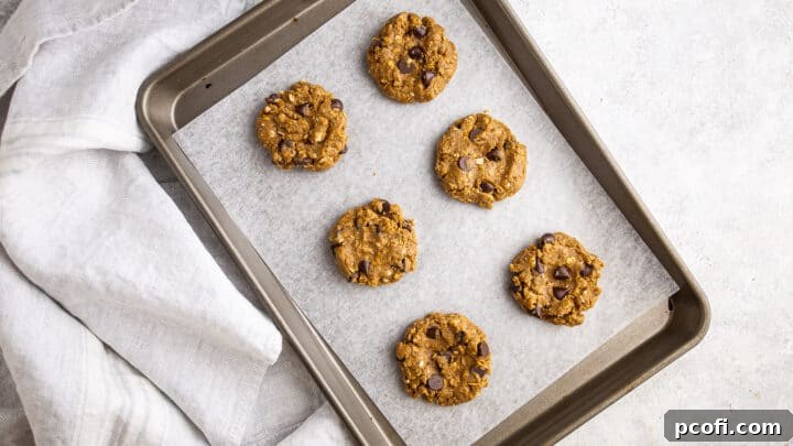 Unbaked protein cookies on a parchment-lined baking sheet.