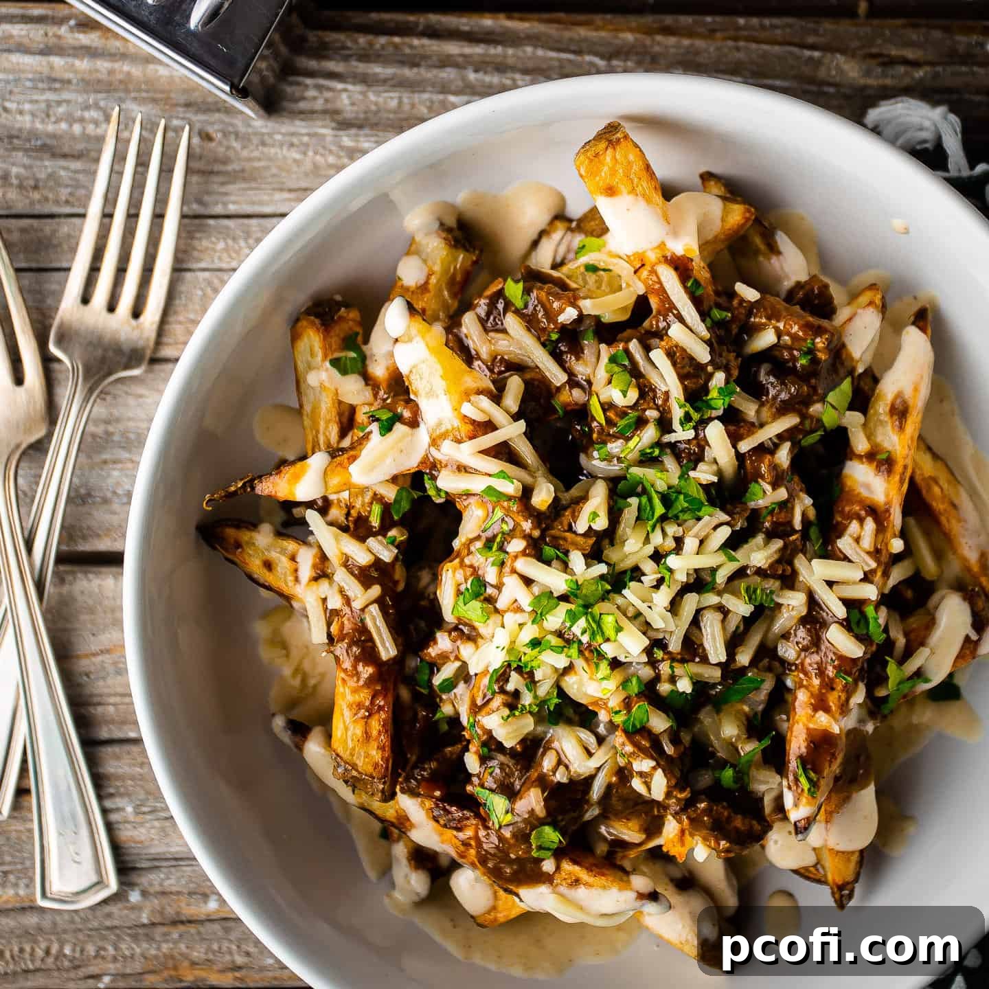 Poutine served in a white bowl on a distressed wooden tabletop, showcasing its crispy fries, rich gravy, and creamy cheese sauce.