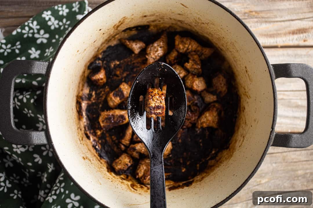 Browning beef cubes in a large enameled cast iron pot to build a rich flavor base for the poutine gravy.