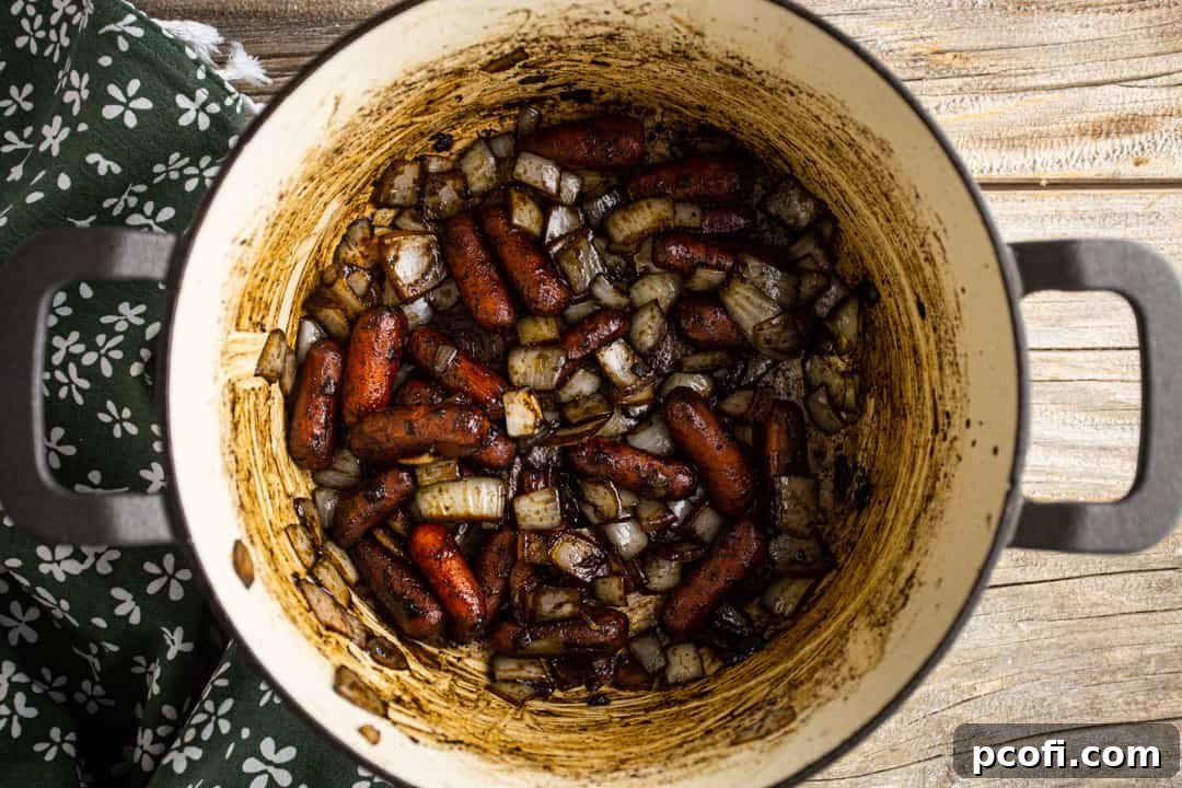 Sauteeing onions and carrots in beef drippings, creating a fragrant base for the poutine gravy.
