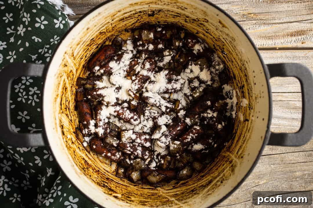 Adding flour to the sautéed vegetables and tomato paste, creating a roux for the gravy.