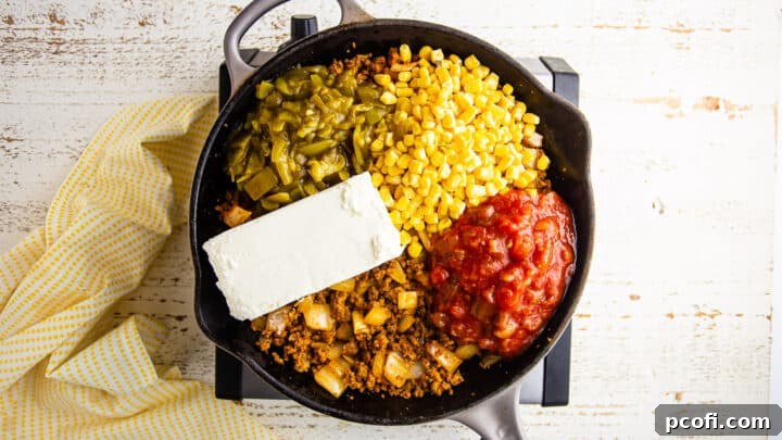 Adding smooth cream cheese to the mixture of chorizo, onions, salsa, and diced green chiles in a skillet, creating the creamy foundation of the corn dip.