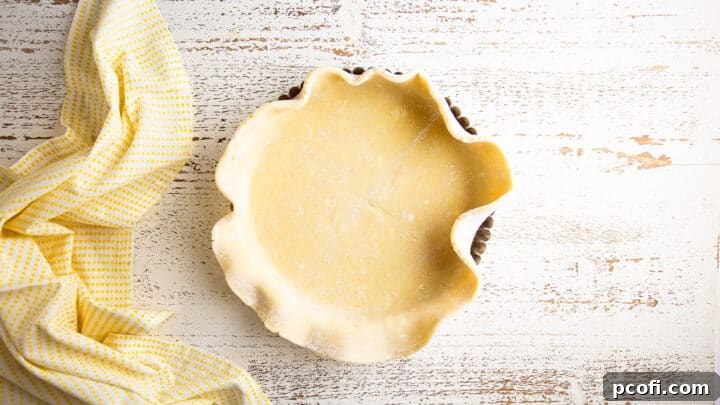 Tart crust dough loosely placed and gently pressed into the tart pan, with excess dough hanging over the edges, before trimming.