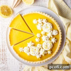 Overhead image of a sliced lemon tart with whipped cream rosettes.