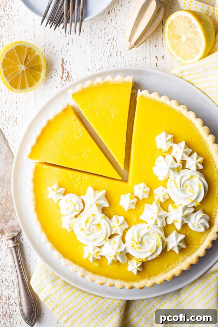 A perfectly baked lemon curd tart, showcasing its golden crust and vibrant yellow filling, artfully arranged with fresh, bright lemons in the background.