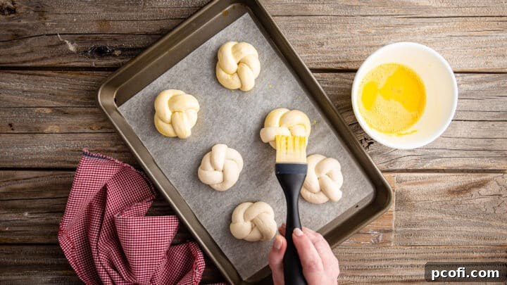 Brushing garlic knots with egg wash.