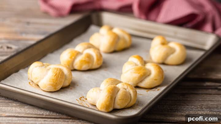 Baked garlic knots on a parchment-lined baking sheet.