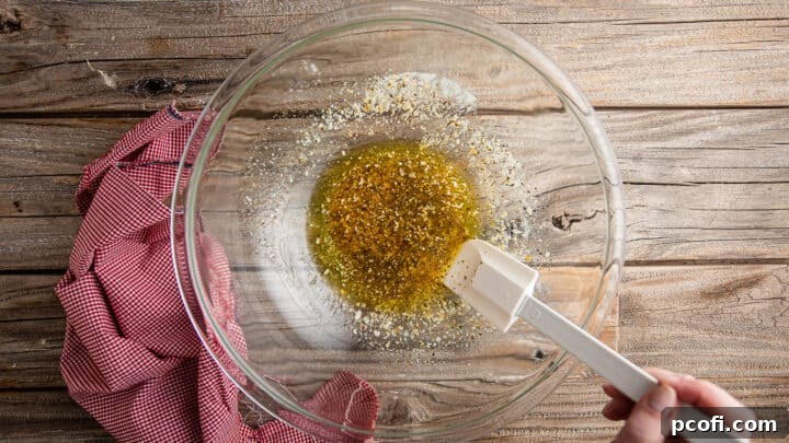 Stirring garlic butter together in a large glass bowl.