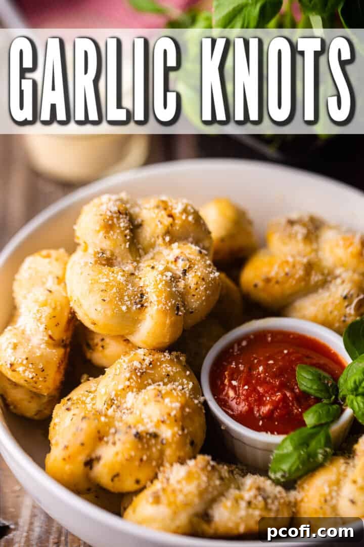 Garlic knot perched in a white bowl with parmesan in the background.