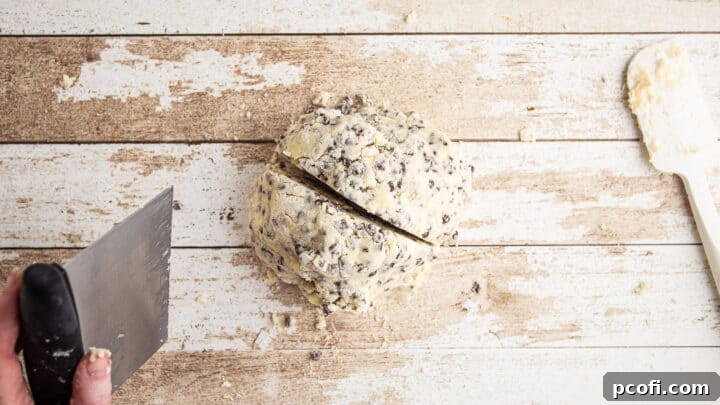 A large clump of chocolate chip scone dough being divided in half.