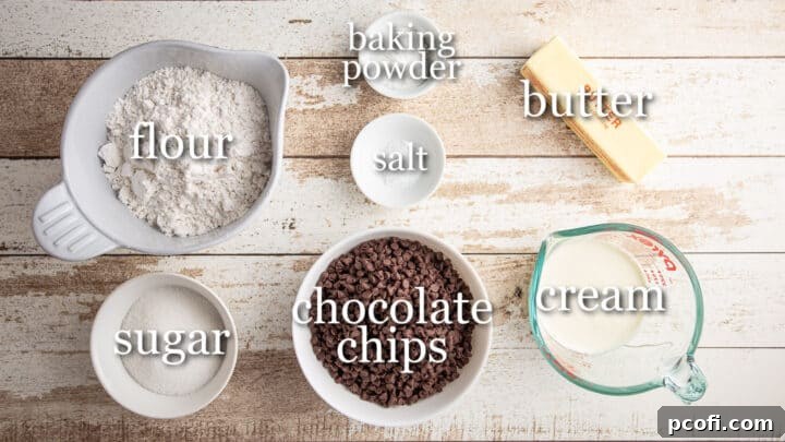 Arrangement of chocolate chip scone ingredients with labels, including flour, sugar, baking powder, salt, butter, chocolate chips, and heavy cream.