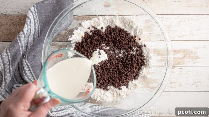 Mini chocolate chips and cold heavy cream being added to the scone dough mixture.