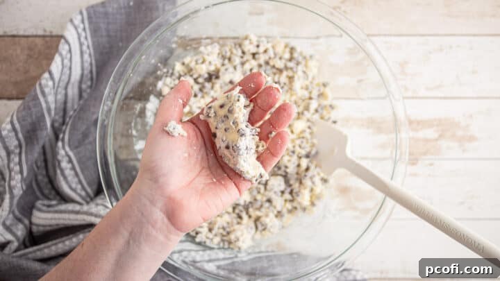 Squeezing a portion of crumbly scone dough in hand to test if it holds together.