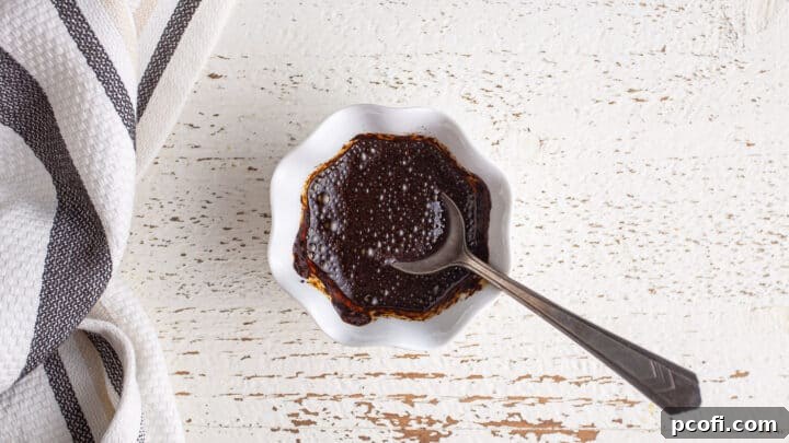 Instant espresso powder being stirred into a small amount of water in a clear glass, creating a concentrated coffee liquid.