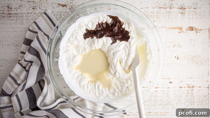 Sweetened condensed milk and the dissolved instant espresso are poured into a large bowl containing whipped cream, ready for blending.