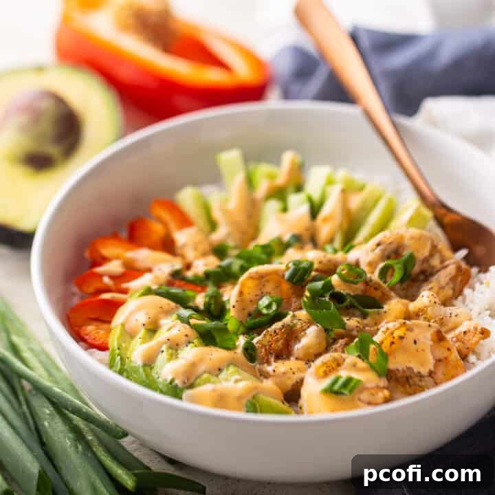 Grilled bang bang shrimp bowl with fresh veggies in the background.