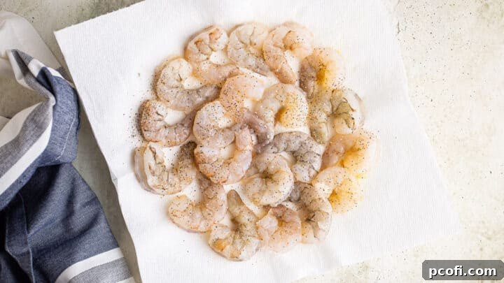Seasoned raw shrimp on a paper towel lined plate.