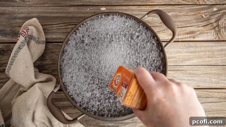 Baking soda being carefully added to a large pot of boiling water, initiating the characteristic fizzing.
