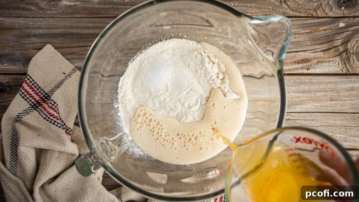 Bowl containing pretzel bun dough ingredients: flour, salt, beer, and melted butter, ready for mixing.