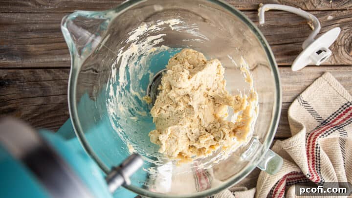 A ball of freshly mixed, slightly shaggy pretzel bun dough in a mixing bowl.