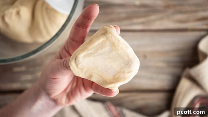 Pretzel bun dough stretched thin, demonstrating it passes the windowpane test.