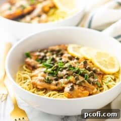Classic chicken piccata served over pasta in a white bowl.