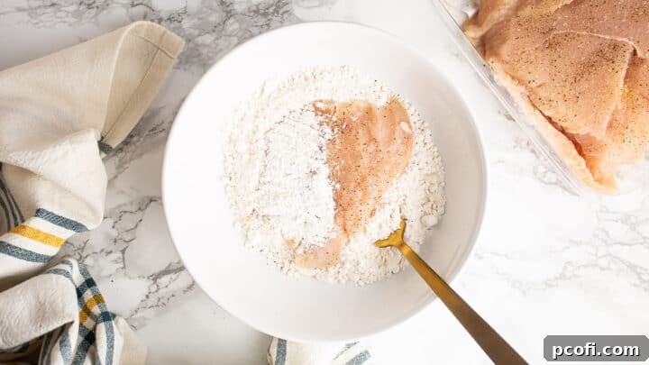 Dredging thin sliced chicken breasts in flour in a shallow bowl.