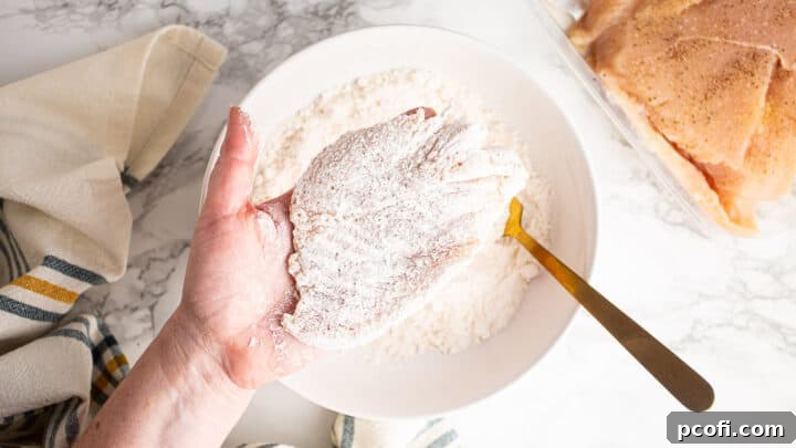A perfectly seasoned and lightly floured chicken cutlet, ready for searing.