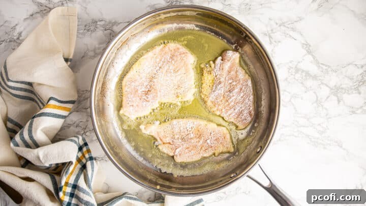 Searing chicken cutlets in a hot skillet with olive oil and butter until golden.
