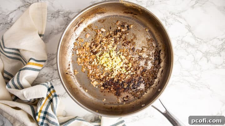 Sautéing finely minced shallots and garlic in a stainless steel skillet, creating the base for the piccata sauce.