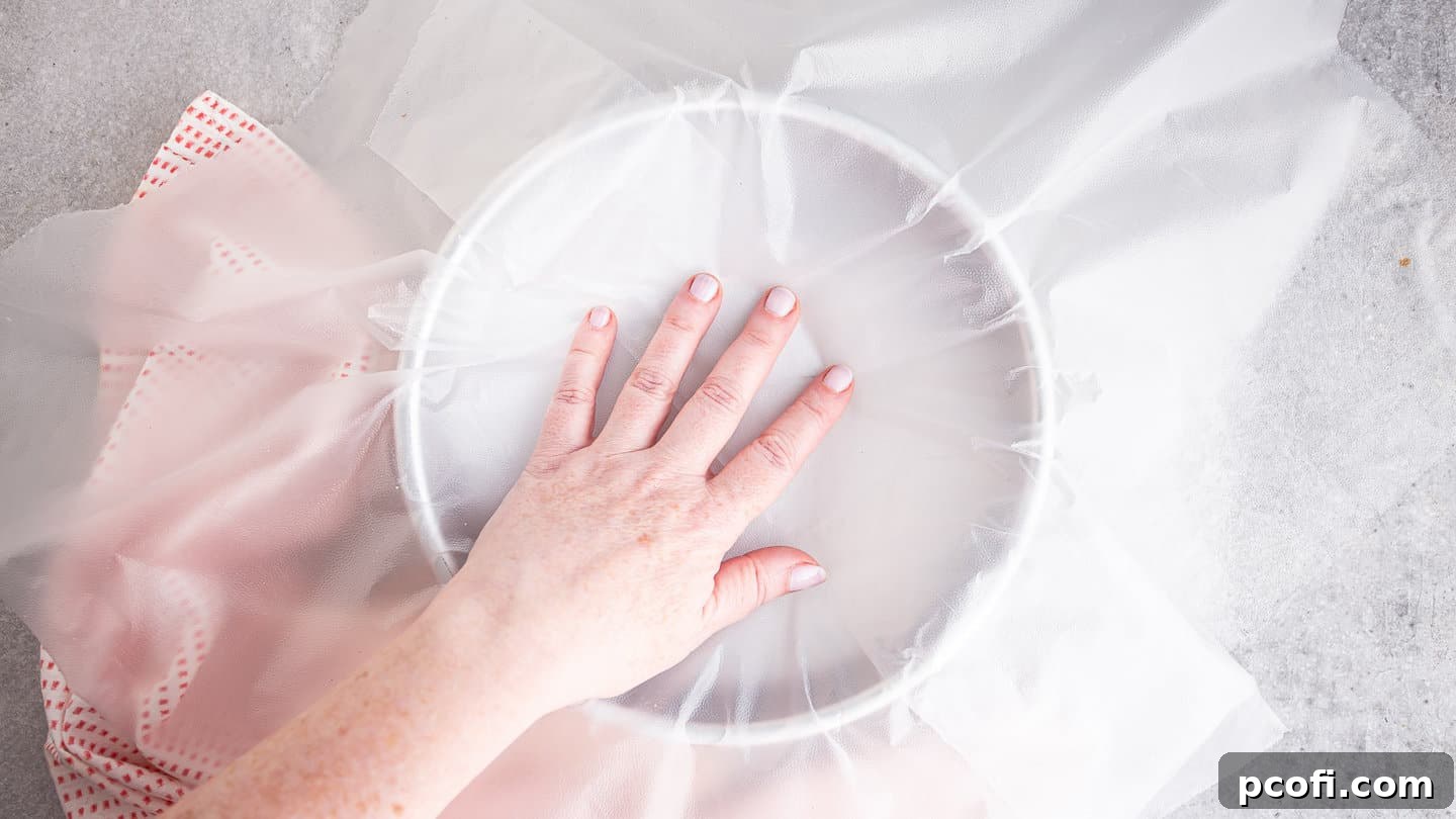 Lining a cake pan with plastic wrap.