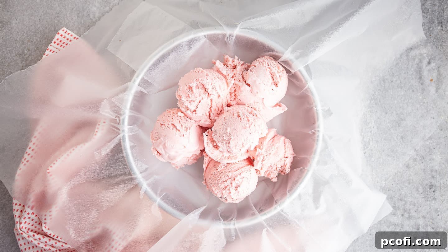 Scoops of strawberry ice cream in a plastic wrap lined cake pan.