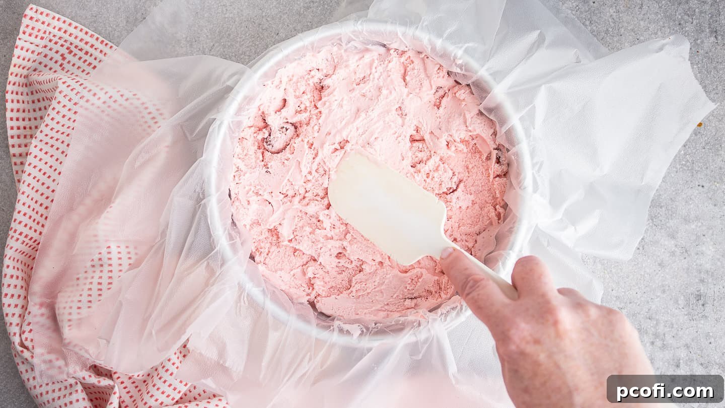 Pressing strawberry ice cream into a cake pan.