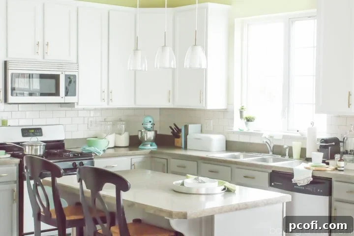 Kitchen close-up featuring new upper white and lower grey cabinets with brass hardware