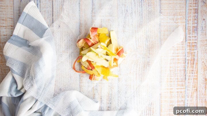 Apple cores and lemon peel are neatly gathered in the center of a square of cheesecloth, ready to be tied into a sachet.