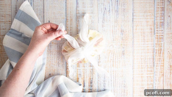 The cheesecloth is being expertly tied into a sachet, securing the apple cores and lemon peel inside.