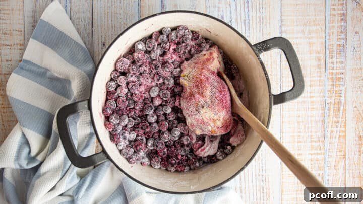 Blueberries are being tossed with sugar and thickeners in a pot to prepare the blueberry crisp filling.
