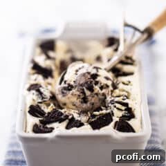 Homemade Oreo ice cream in a white ceramic loaf pan with a vintage ice cream scoop.