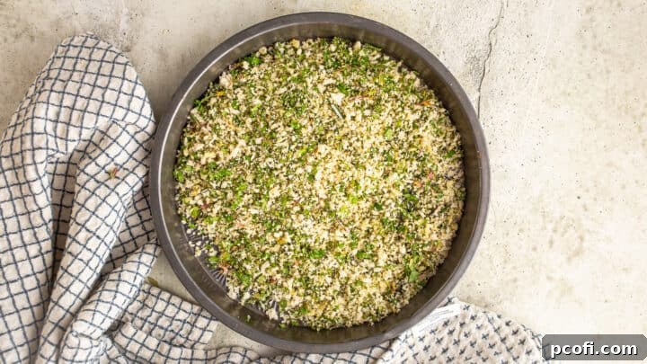 A close-up of beautifully mixed herbed bread crumbs, ready for coating, resting in a charming vintage cake pan.