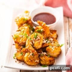 Coconut shrimp presented on a rectangular platter with dipping sauce.