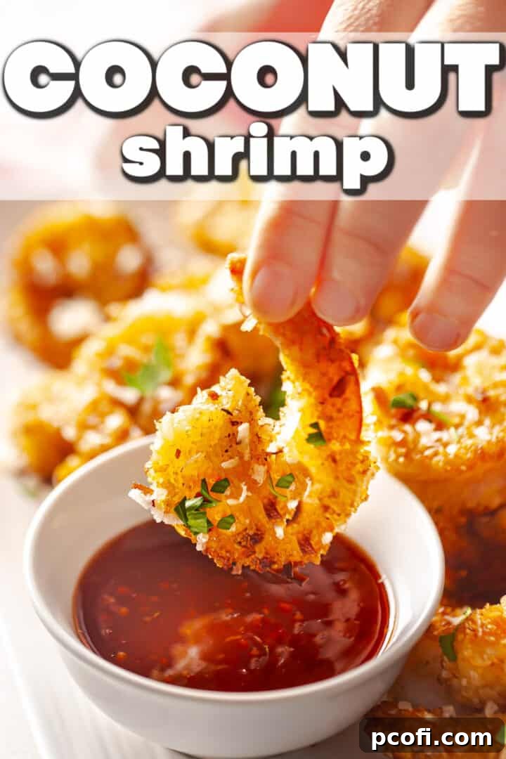 A crispy coconut shrimp being dipped into a sweet chili sauce, highlighting its golden texture.