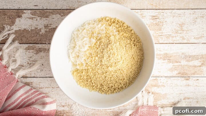 Shredded coconut and panko breadcrumbs expertly combined in a shallow white bowl, forming the breading mixture.