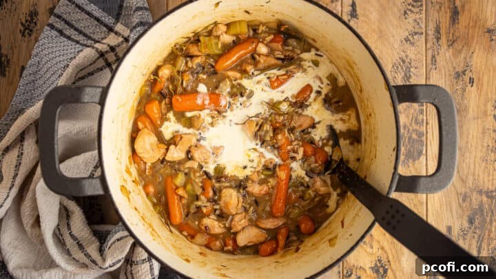 Adding cream to chicken and wild rice soup.