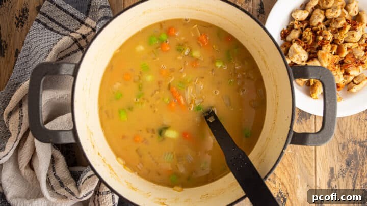 Adding chicken stock to vegetables and roux.