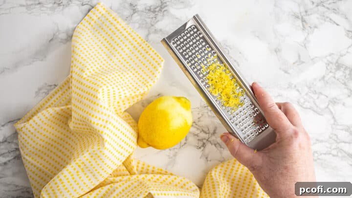 Zesting a lemon with a microplane, showing the fine zest being removed.
