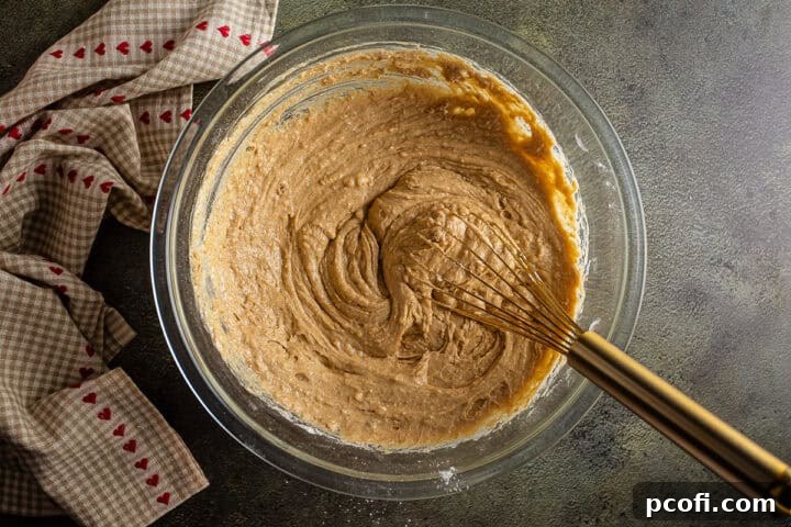 The fully mixed apple bread batter, smooth with a few small lumps, ready for assembly in a large mixing bowl.